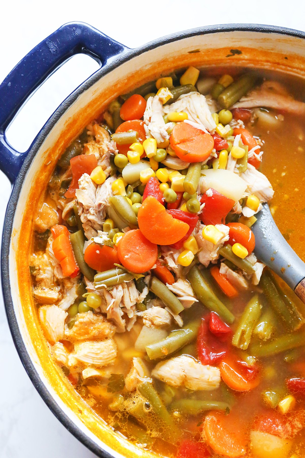 Dutch oven filled with soup that has tons of veggies and chicken and broth.