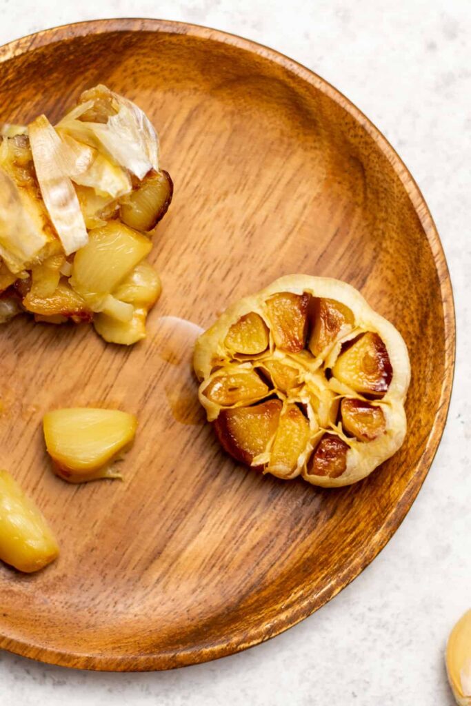 Air fryer roasted garlic on a wooden trivet. 