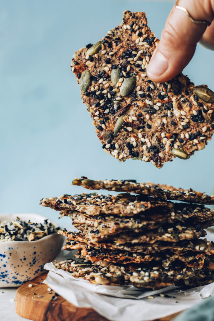 Hand picking up an easy seed cracker with everything bagel seasoning. 