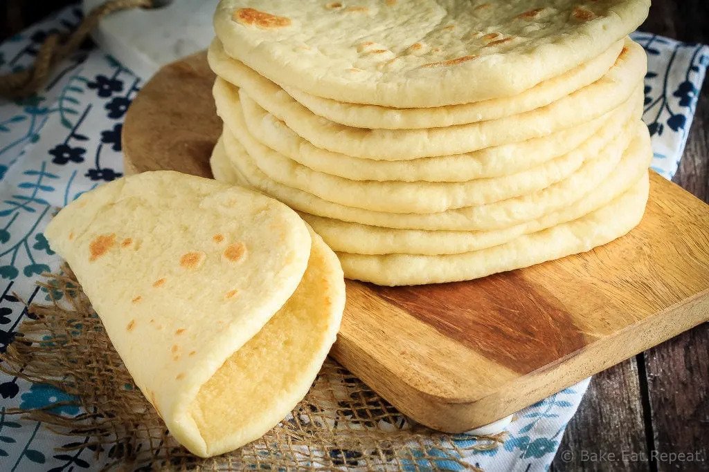 Soft flatbread in a stack on a cutting board. 