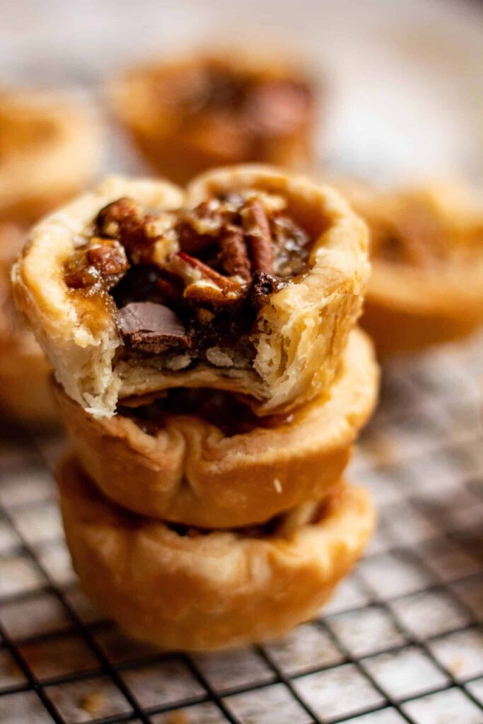 Stack of 3 mini butter tarts with a bite missing from the top one. 