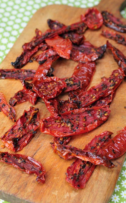 Homemade sun-dried tomatoes laying on a cutting board. 