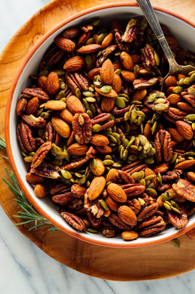 Bowl with a spoon tucked into the sweet and spicy roasted party nuts. 