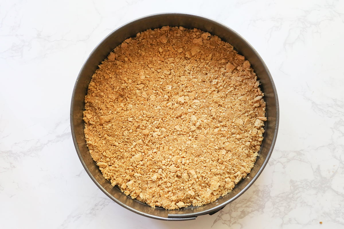 Top view of a graham cracker crust inside a springform pan.