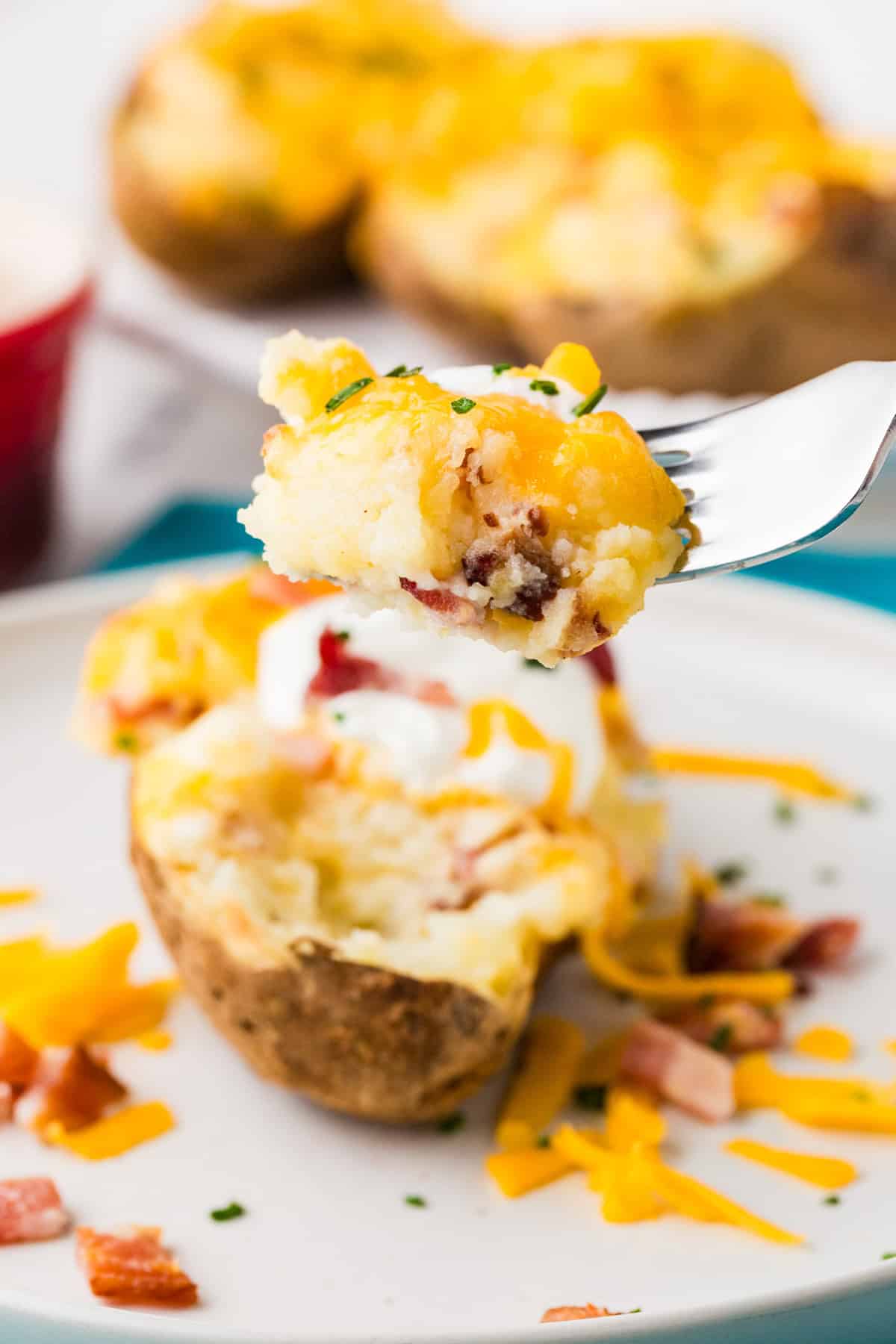 Fork lifting a cheesy bite of potato from a stuffed potato.
