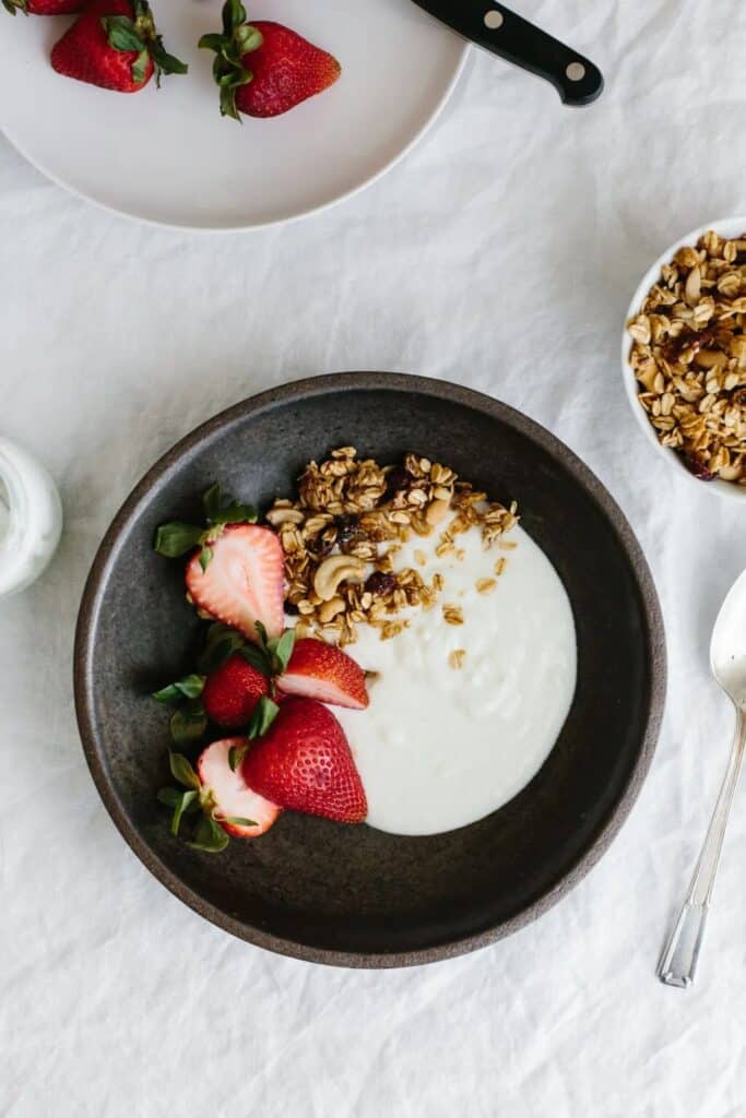 Homemade yogurt with fresh strawberries and granola garnished over it. 