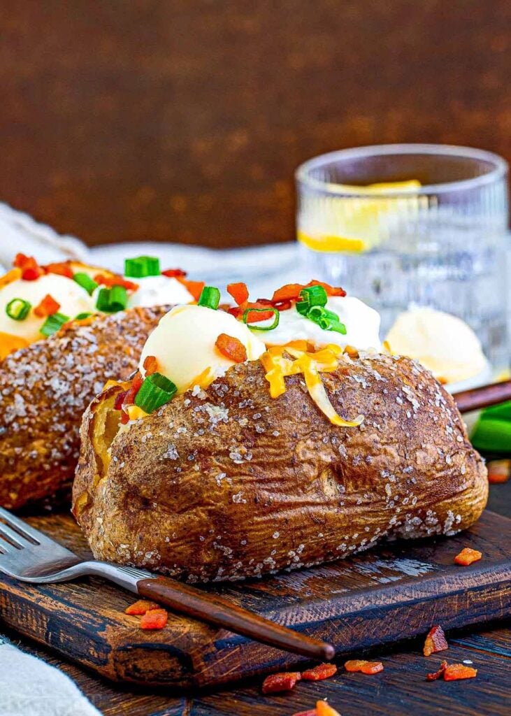 Loaded baked potatoes on a cutting board. 