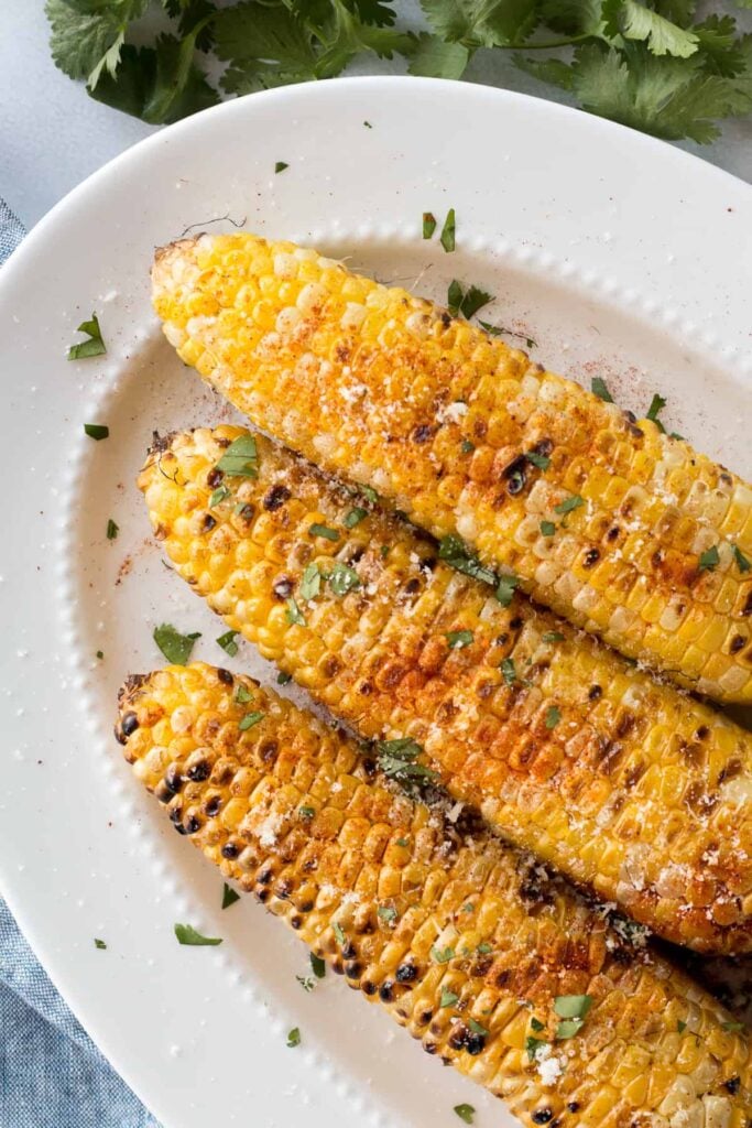 3 grilled corn on the cobs with butter and chopped cilantro. 