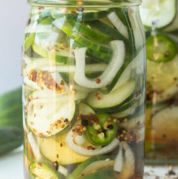 Homemade sweet pickles with cucumbers, onions, and spices in a glass jar.