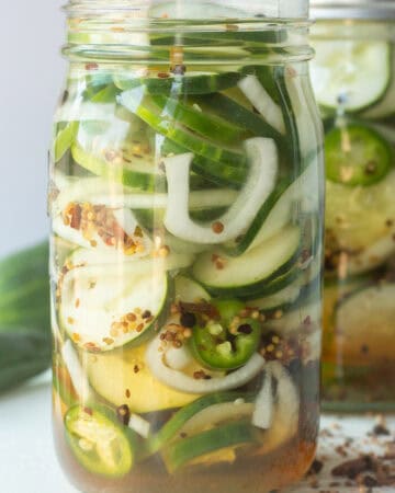 Homemade sweet pickles with cucumbers, onions, and spices in a glass jar.