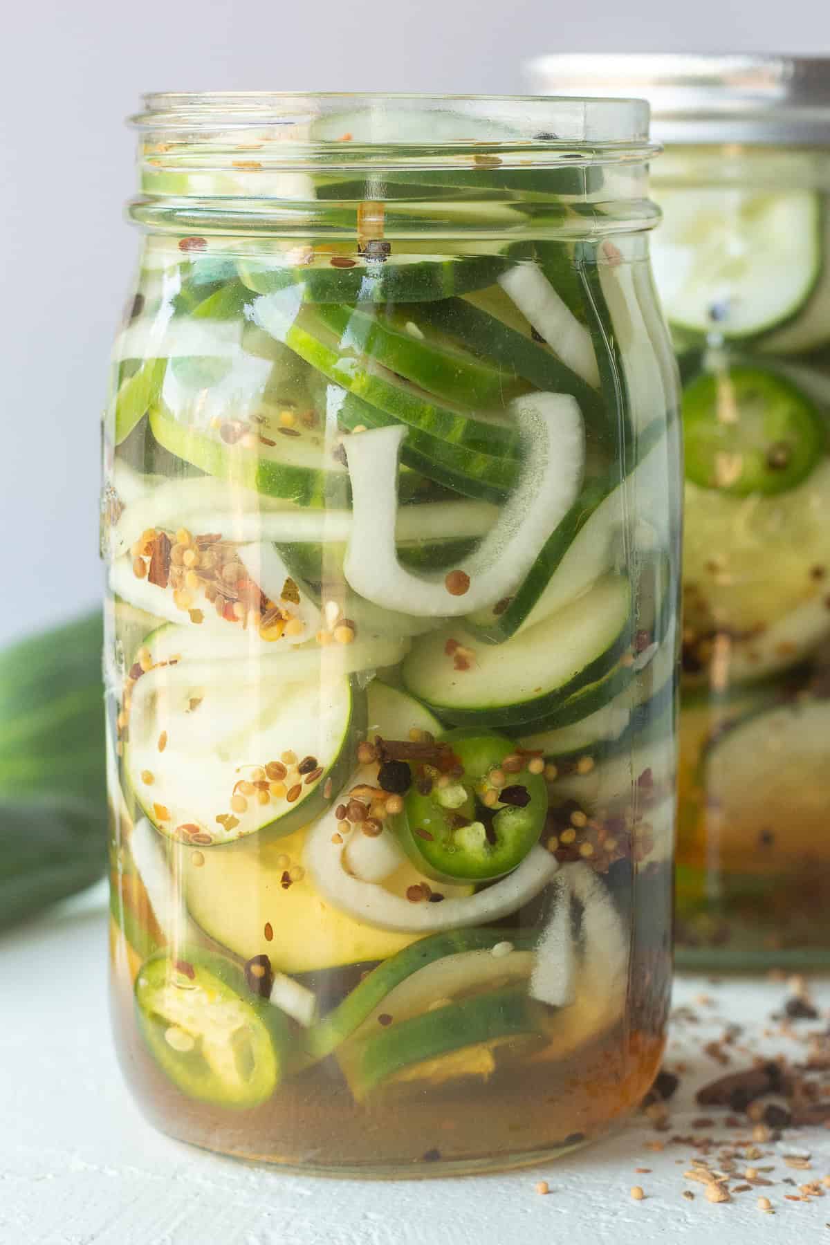 Homemade sweet pickles with cucumbers, onions, and spices in a glass jar.