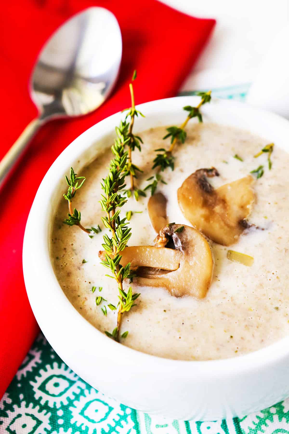 Bowl of mushroom soup with fresh thyme and sauteed mushrooms garnished on top. 