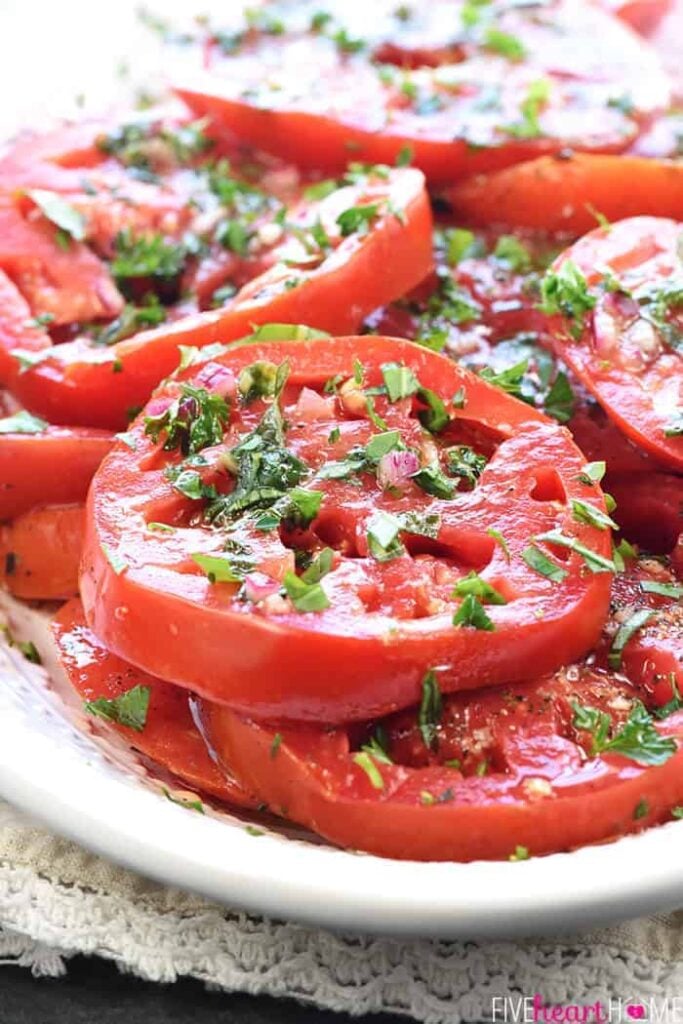 Marinated tomatoes on a white serving plate. 