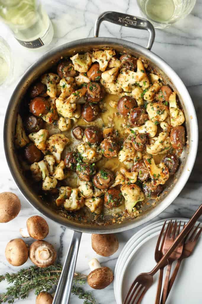 Garlic butter mushrooms and cauliflower in a skillet. 