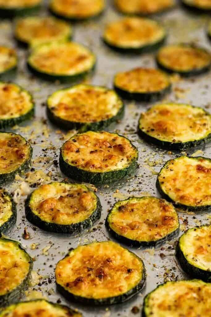 Baked parmesan zucchini laying on a baking sheet. 