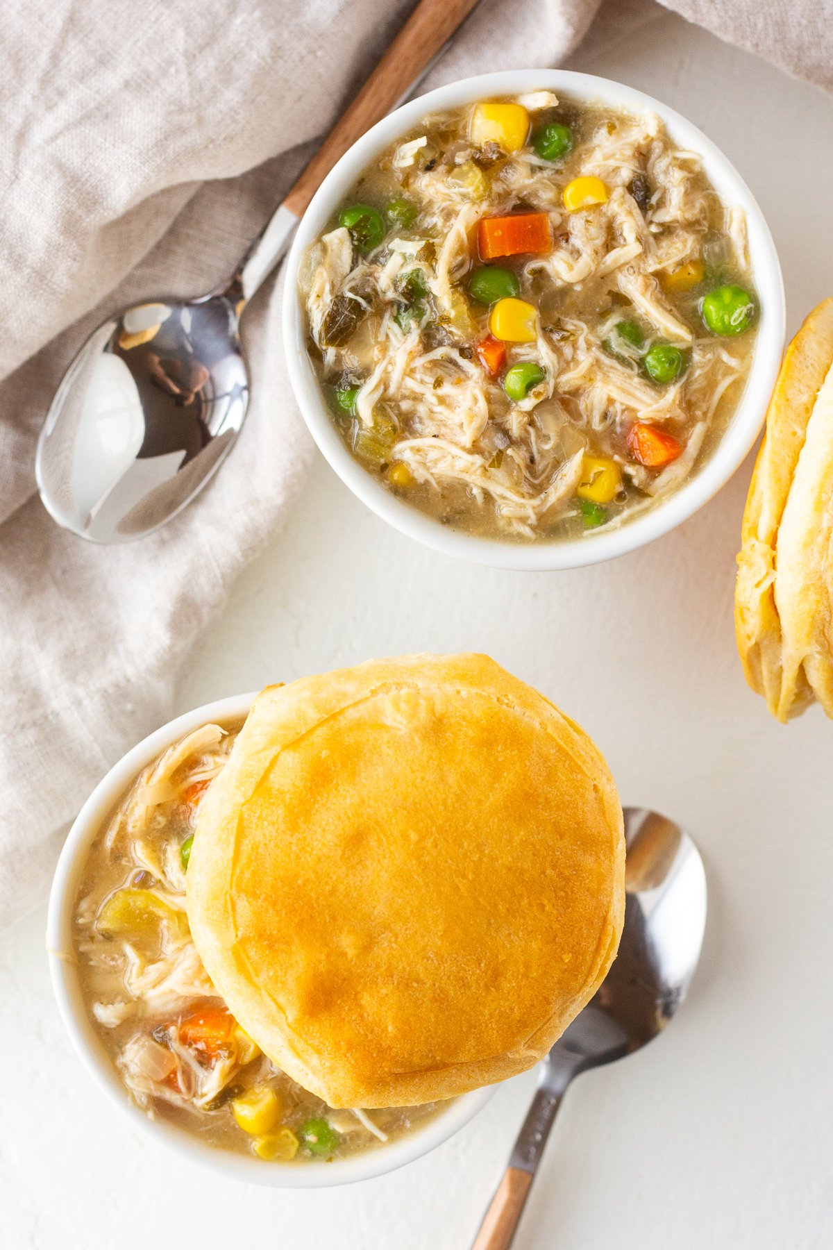Top view of two bowls of chicken pot pie, one topped with a biscuit.
