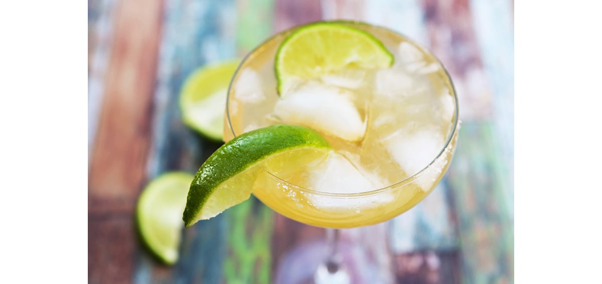 Looking down into a margarita filled with ice and with a lime wedge on the edge of the glass.