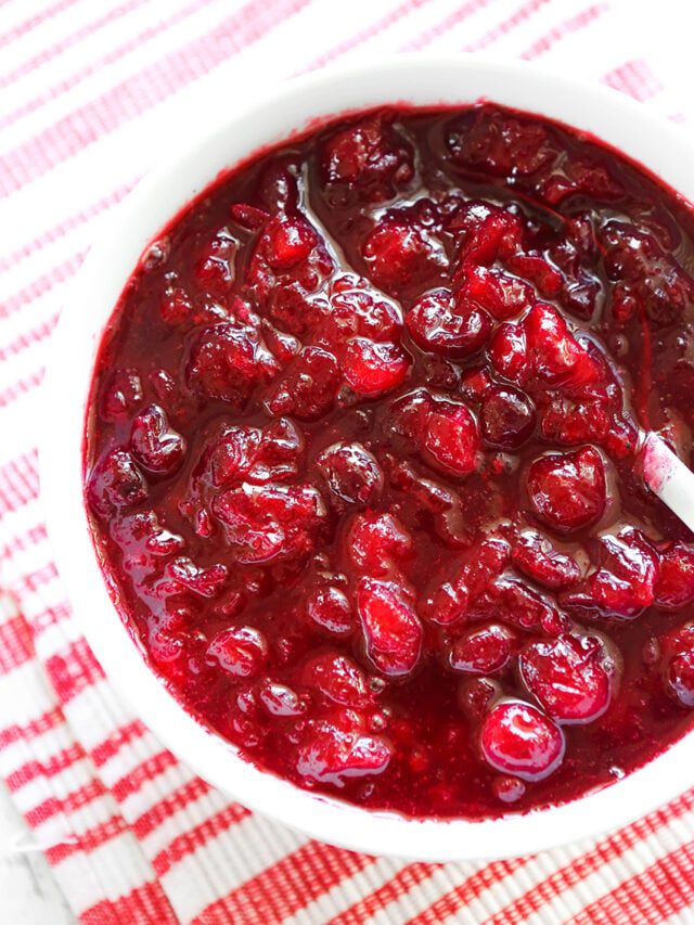 Bowl of cranberry sauce with a spoon resting in it. 