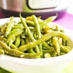 Fresh green beans cooked with garlic butter in a white bowl.