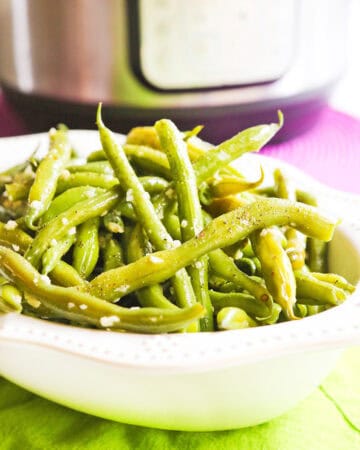 Fresh green beans cooked with garlic butter in a white bowl.