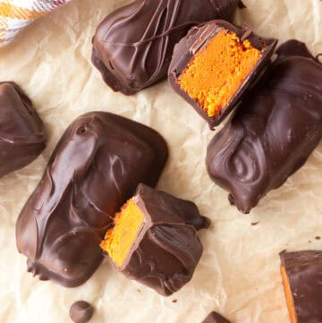 Chocolate-covered homemade Butterfingers with orange filling on parchment paper.