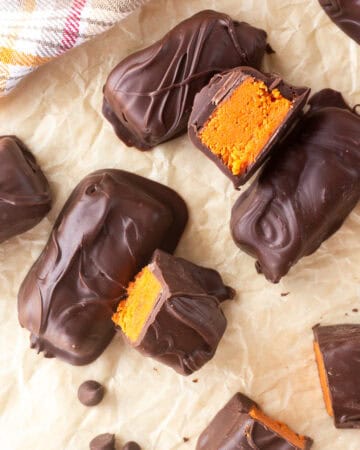 Chocolate-covered homemade Butterfingers with orange filling on parchment paper.