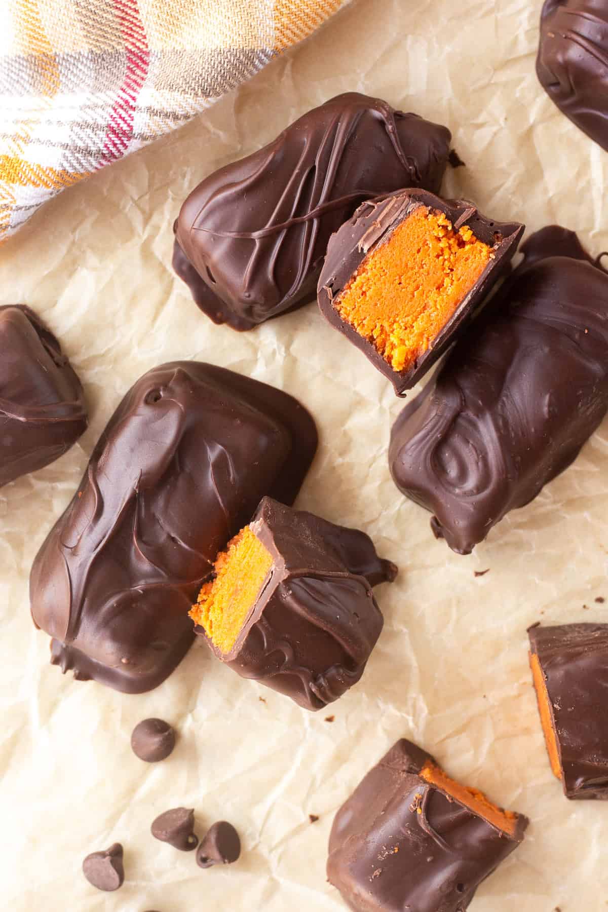 Chocolate-covered homemade Butterfingers with orange filling on parchment paper.