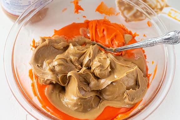Creamy homemade butterfingers mixture in a glass bowl with a spoon.