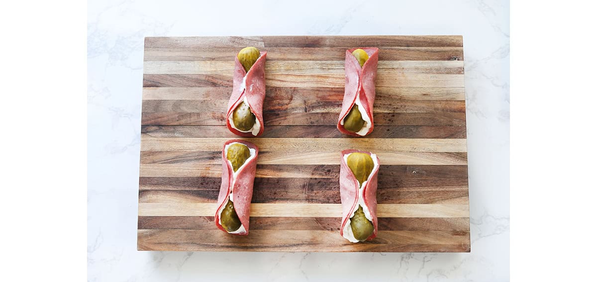 rolled pickle rollups ready to cut on cutting board.