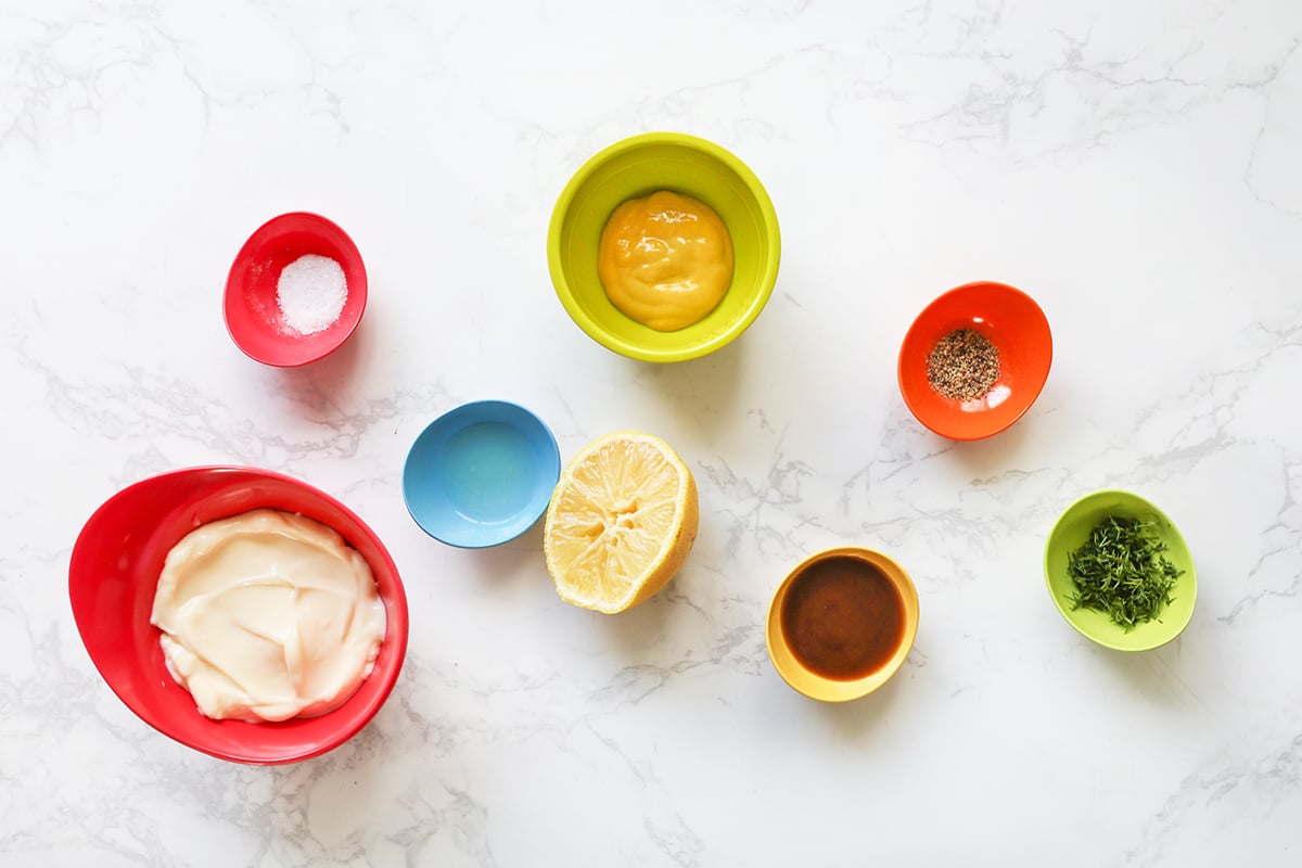 Small colorful bowls of ingredients lined up on a white counter.