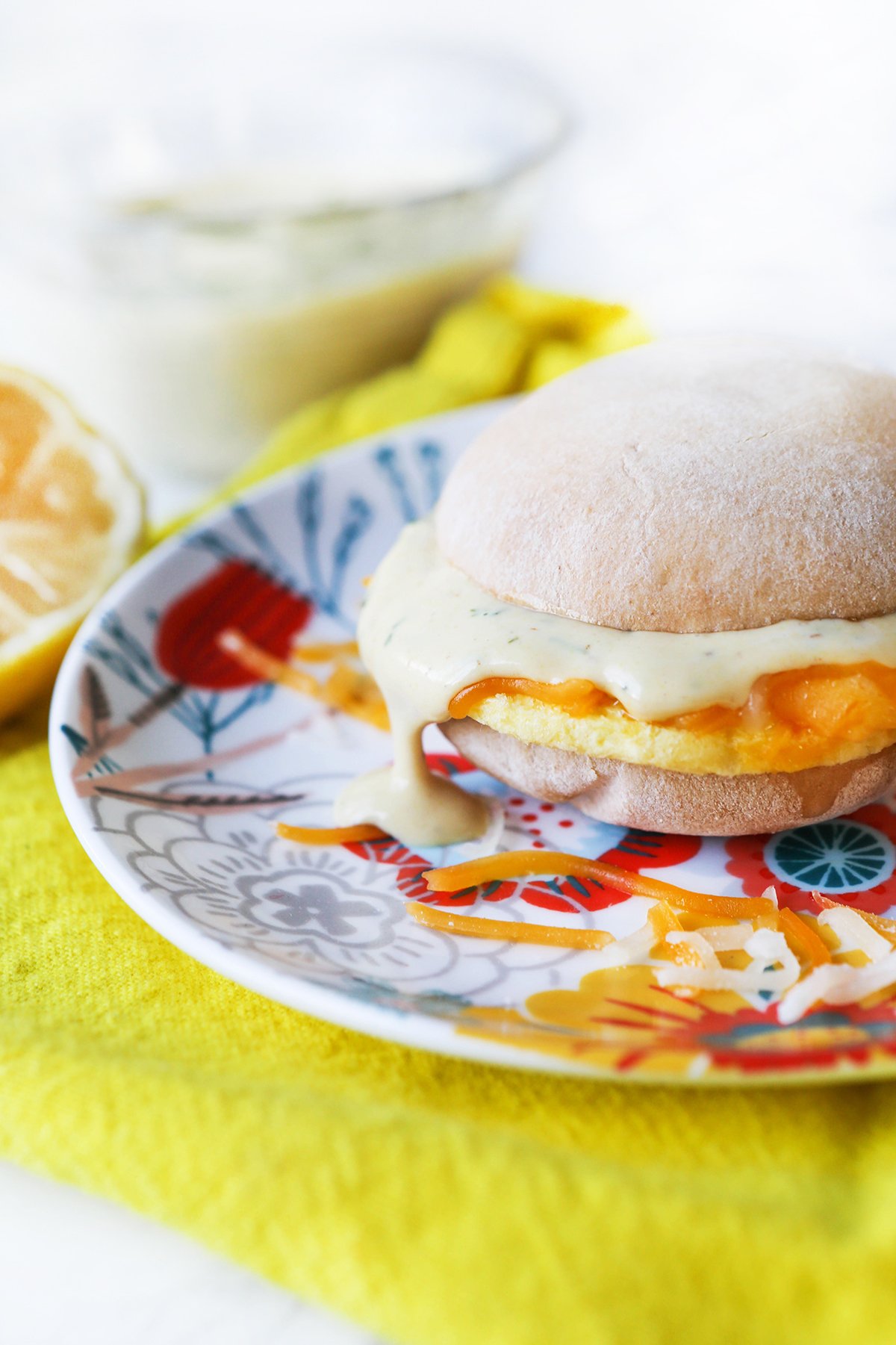 Breakfast sandwich on a plate with sauce dripping off over the side.