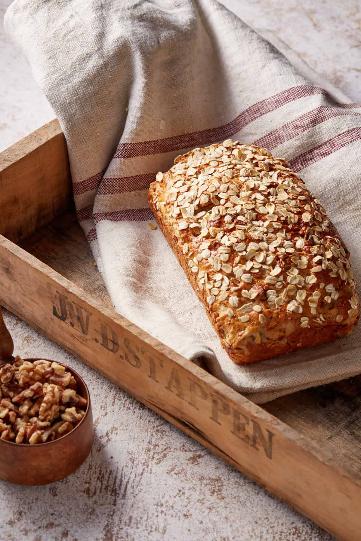 Loaf of apple cinnamon bread with oatmeal on a kitchen towel. 