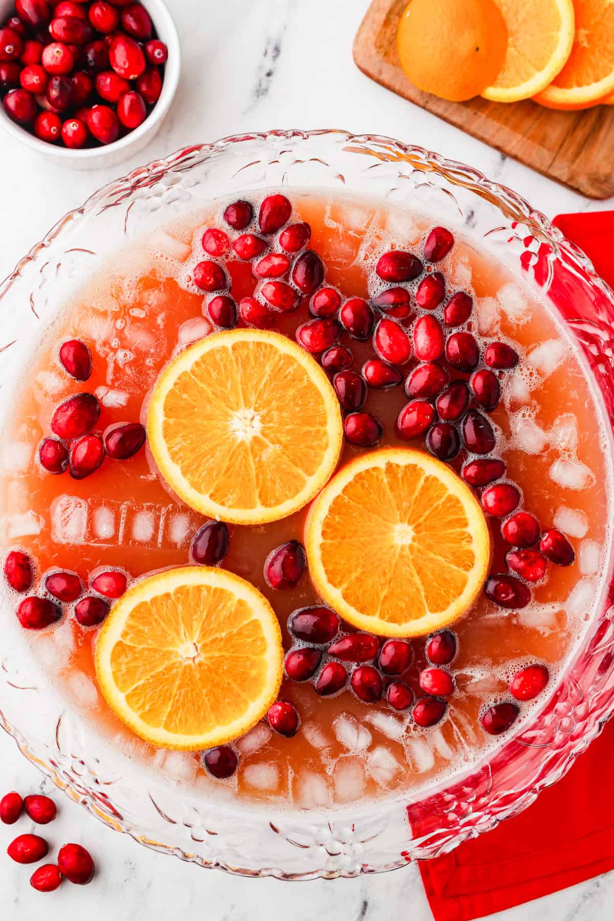 Top view of a punch bowl filled with punch, with cranberries and orange slices floating on top.