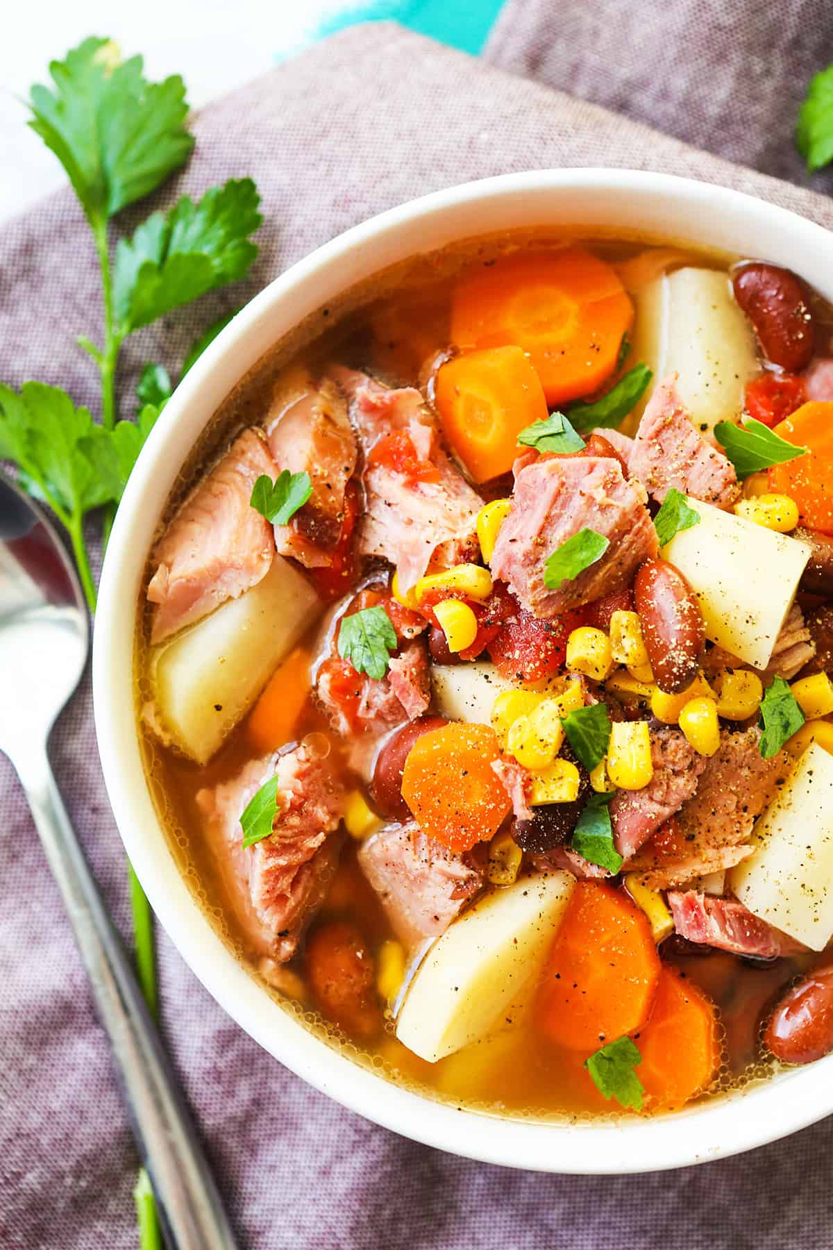 Close up top view of a loaded bowl of ham and vegetable soup with potatoes.