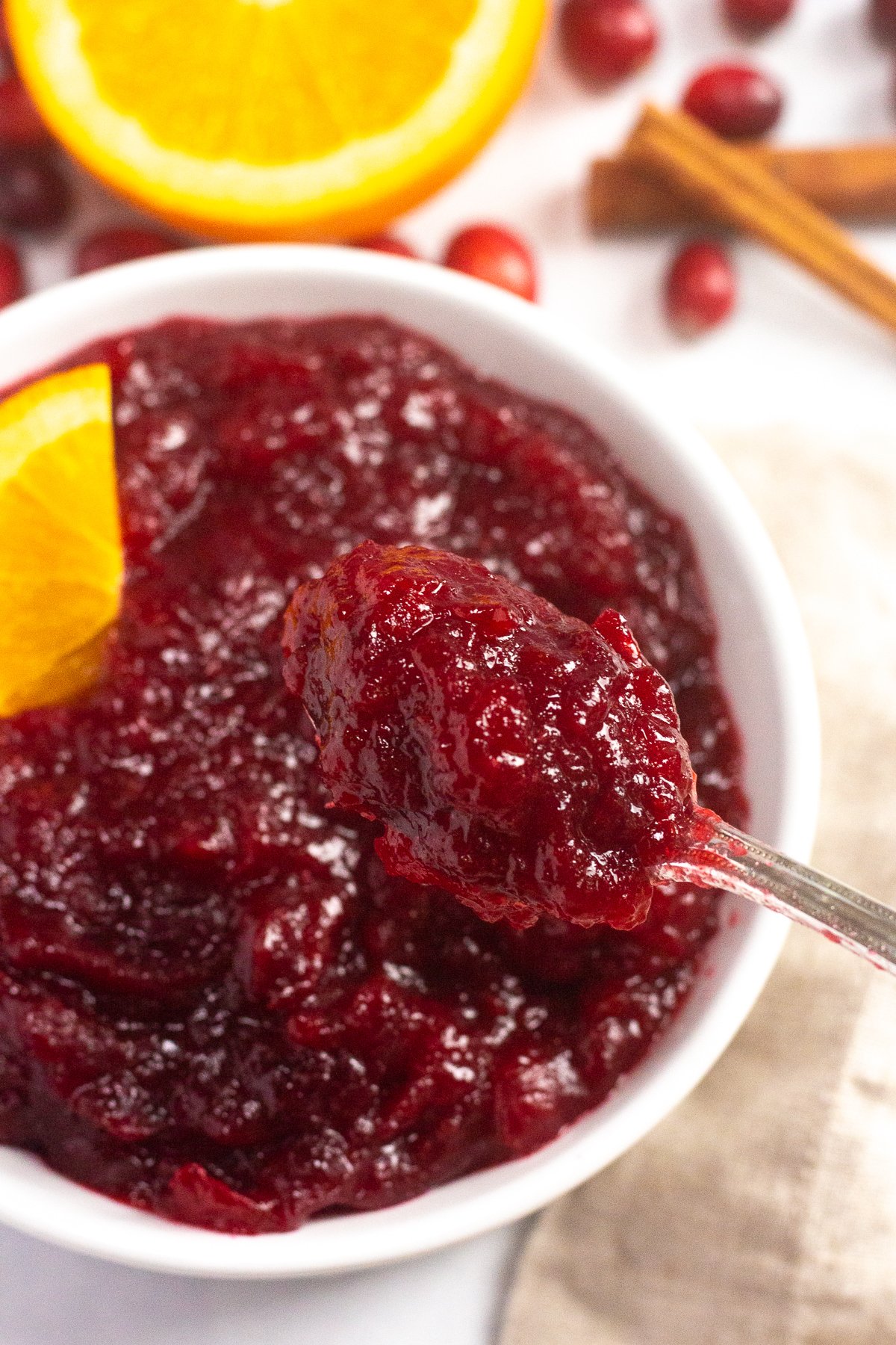 Spoonful of cranberry sauce hovering over serving bowl.