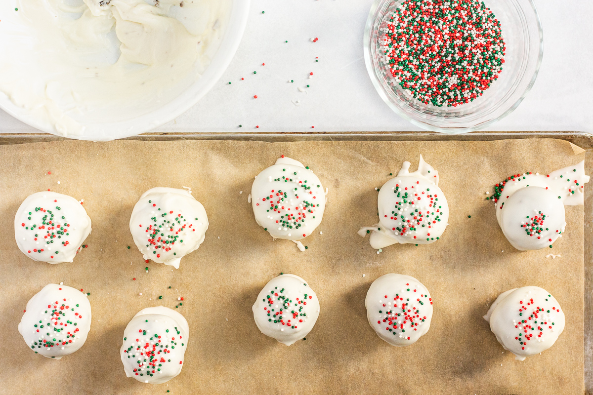 Oreo balls topped with festive sprinkles on a baking sheet.