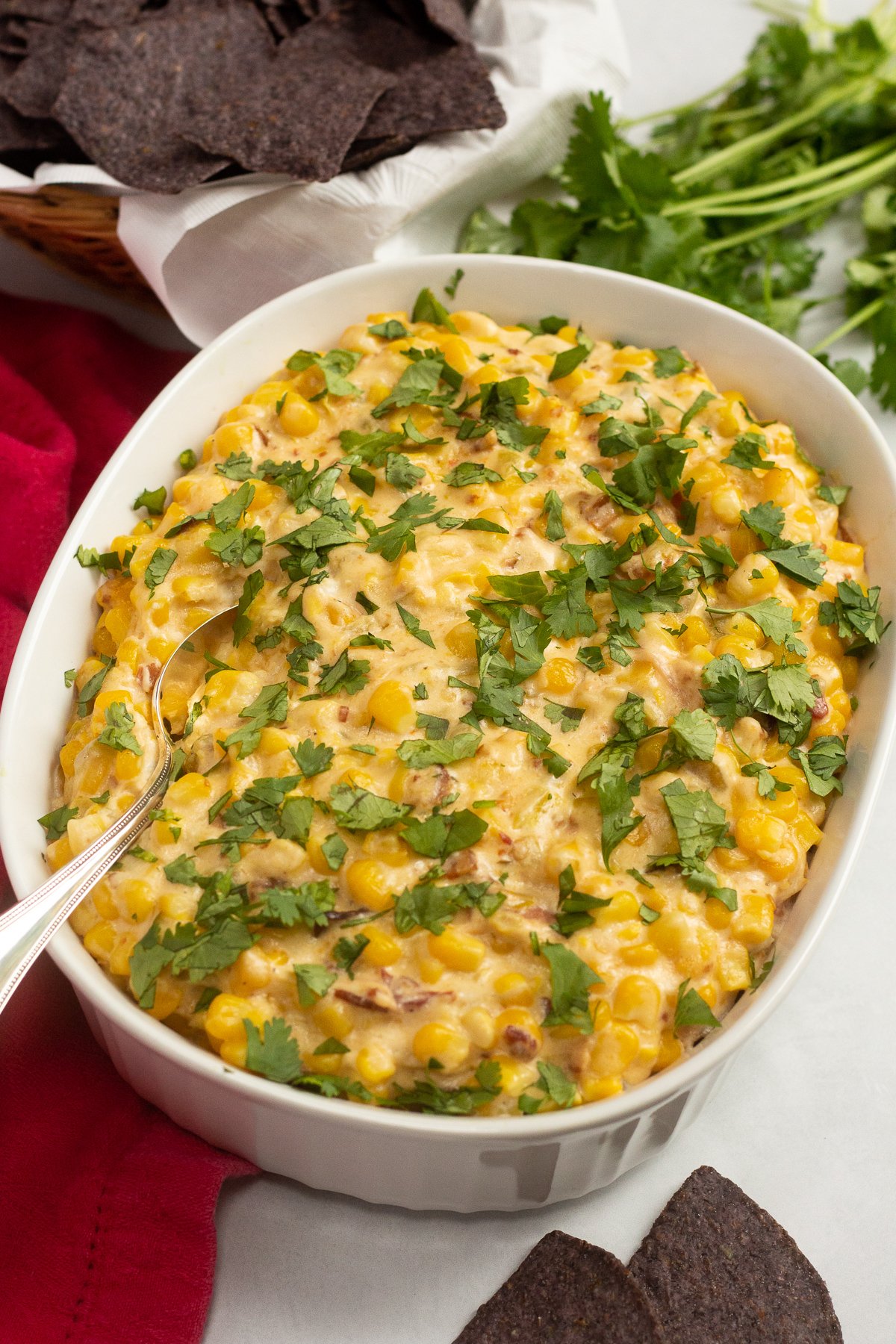 Serving bowl filled with cheesy corn dip and cilantro on top.