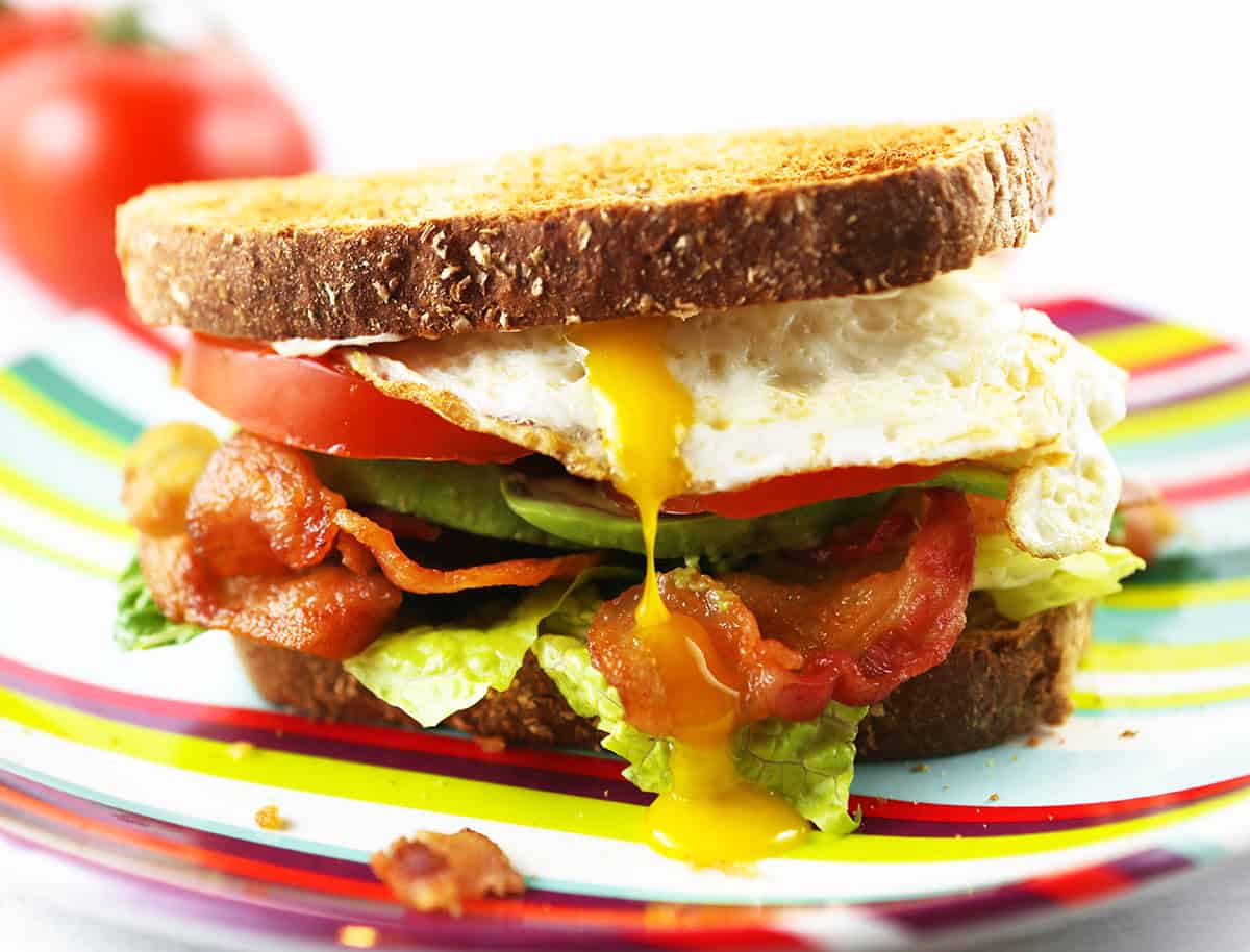 BLT sandwich with egg dripping yolk down the side.