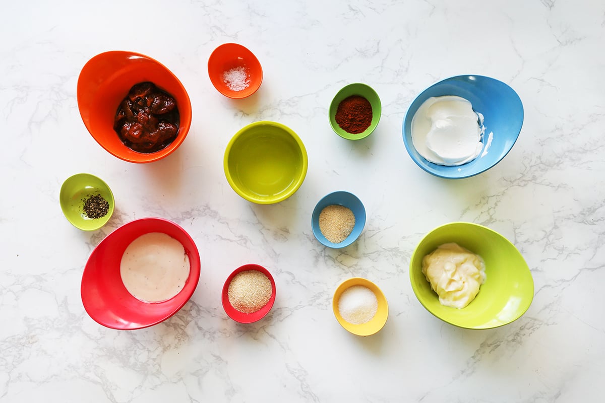 Sauce ingredients in individual small bowls lined up on a white counter.