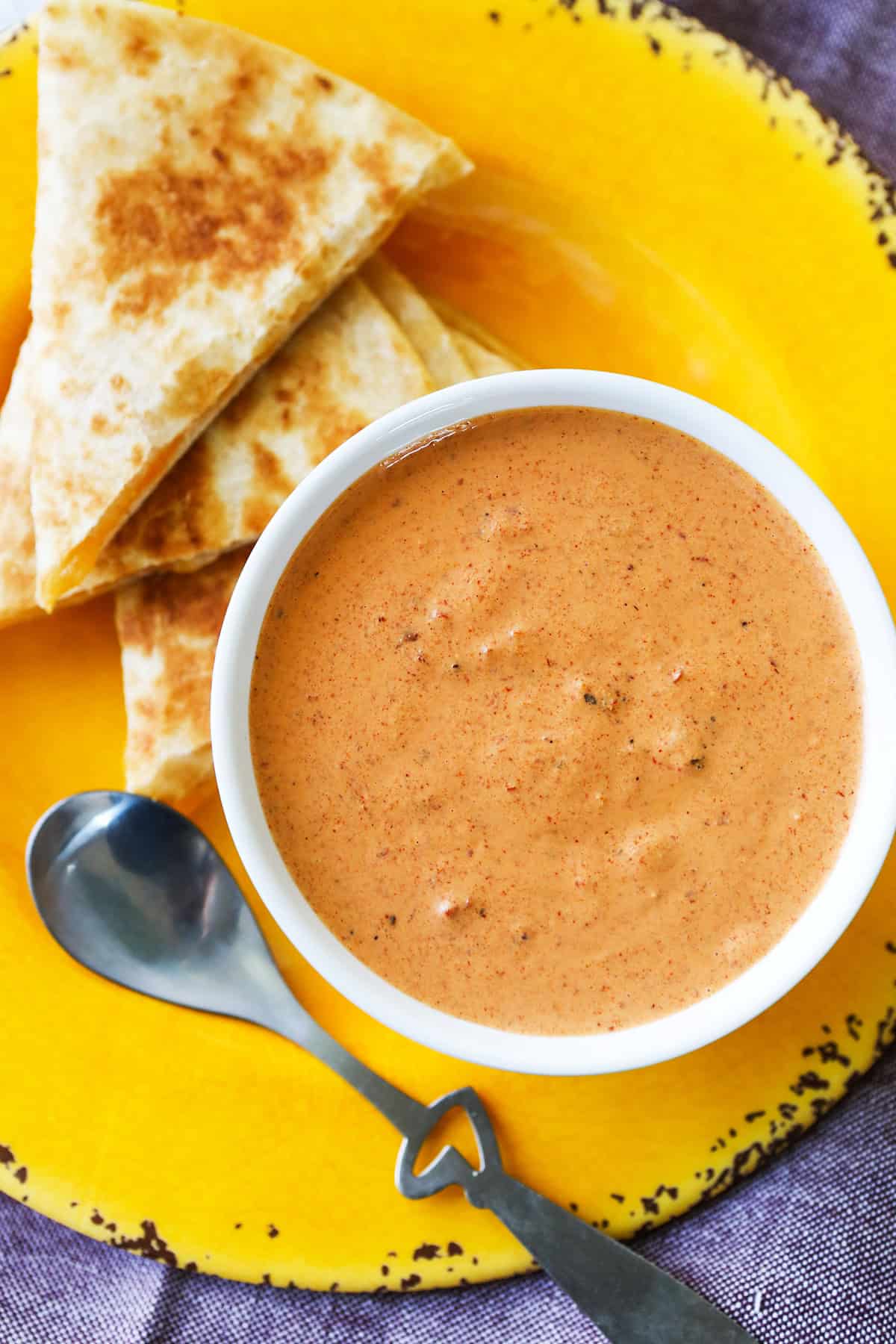 Bowl of chipotle sauce sitting next to a stack of quesadillas.