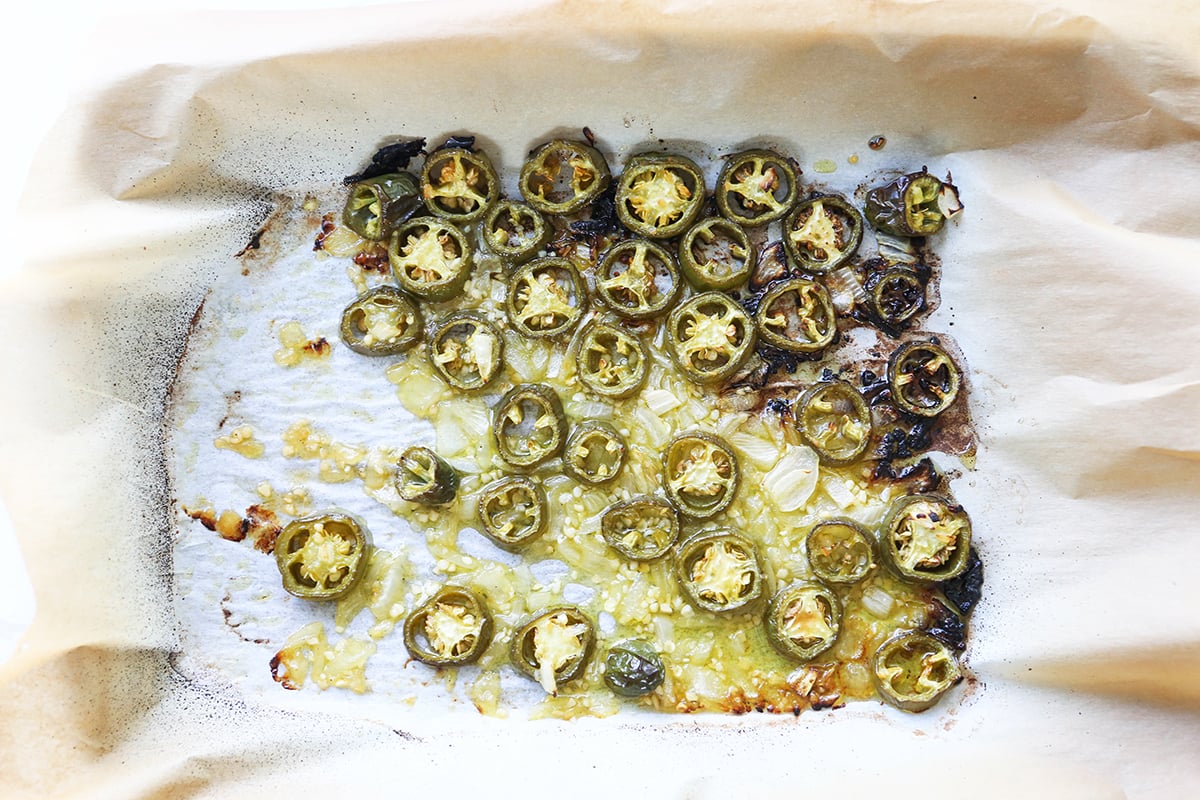 Roasted jalapeno slices on parchment paper.