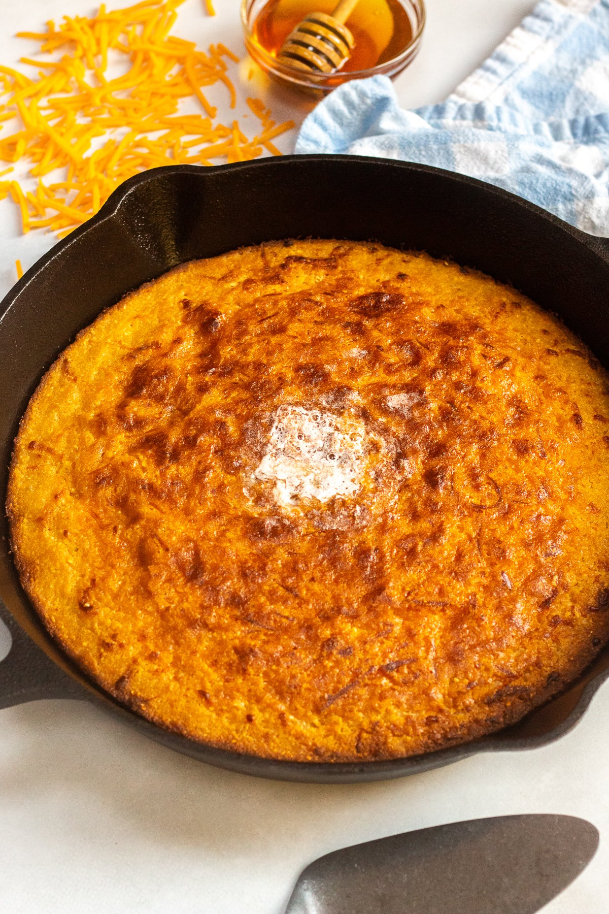 Cast iron skillet with baked corn bread and a pat of butter on top.