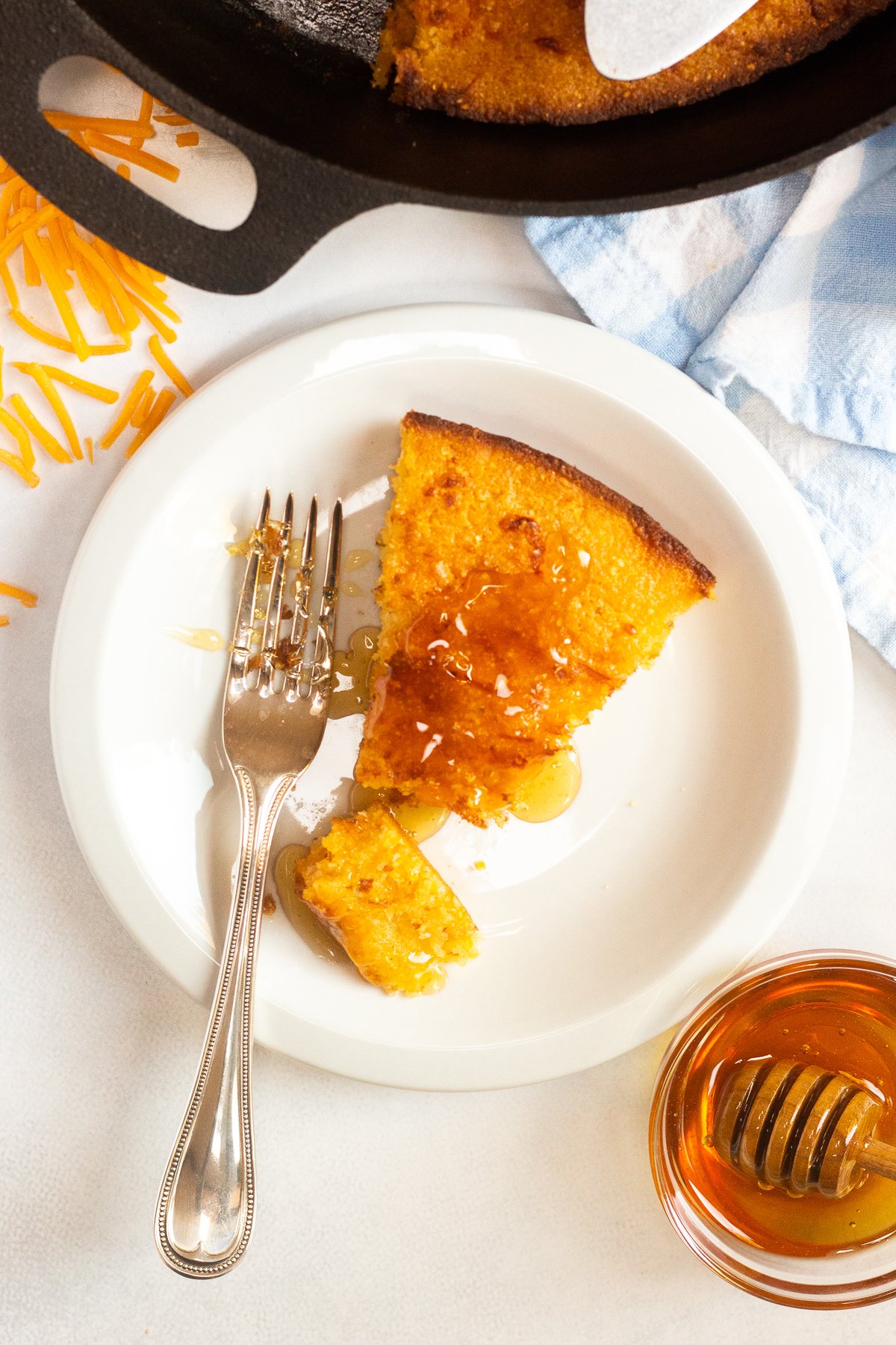 Slice of cornbread drizzled with honey on a plate.
