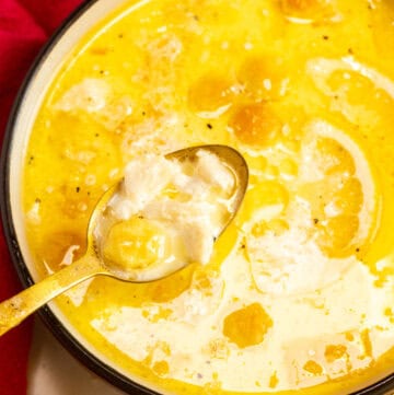 Creamy crab soup with chunks of crab meat and a lemon wedge in the background.