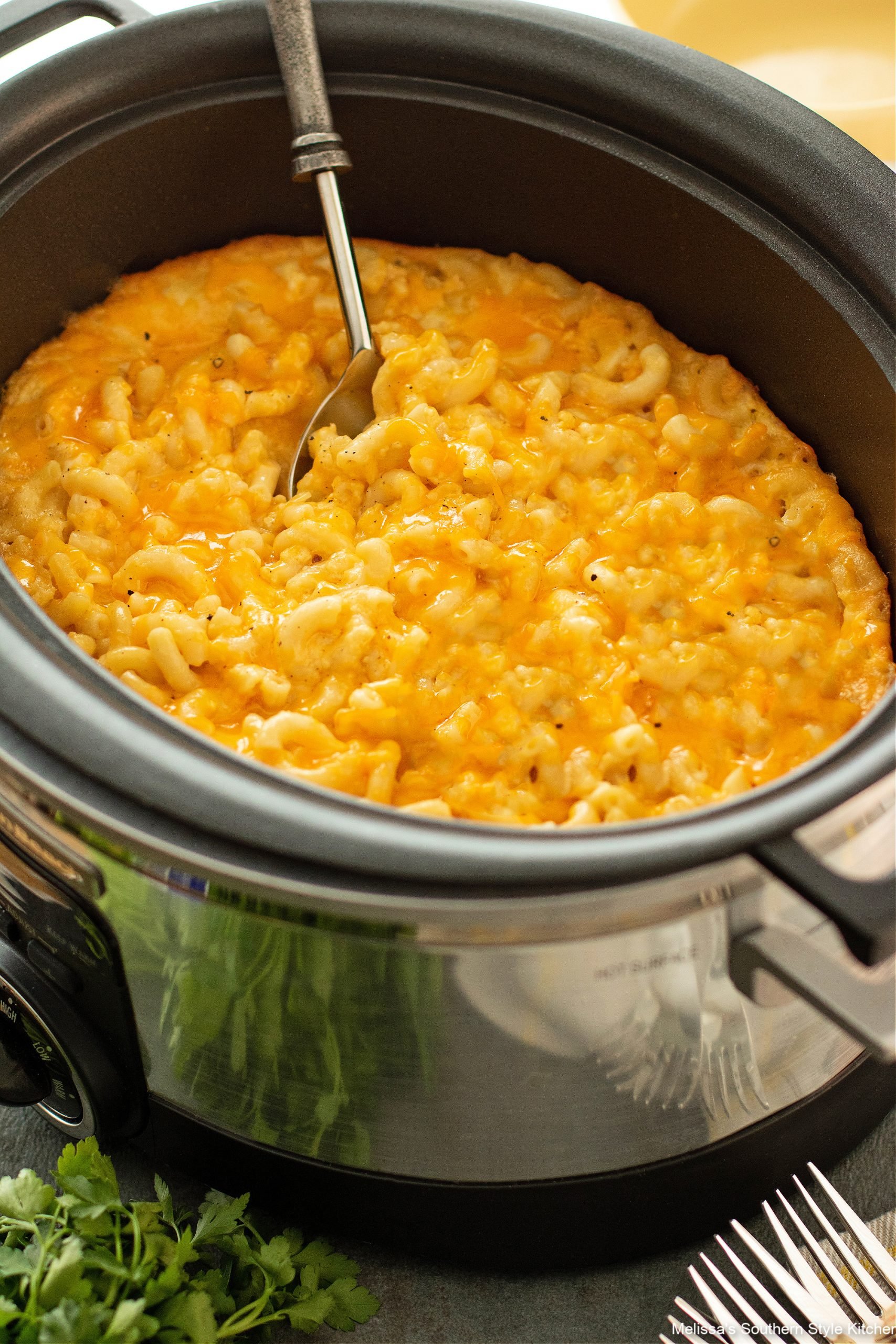 Crockpot full of mac and cheese with a serving spoon full of it. 