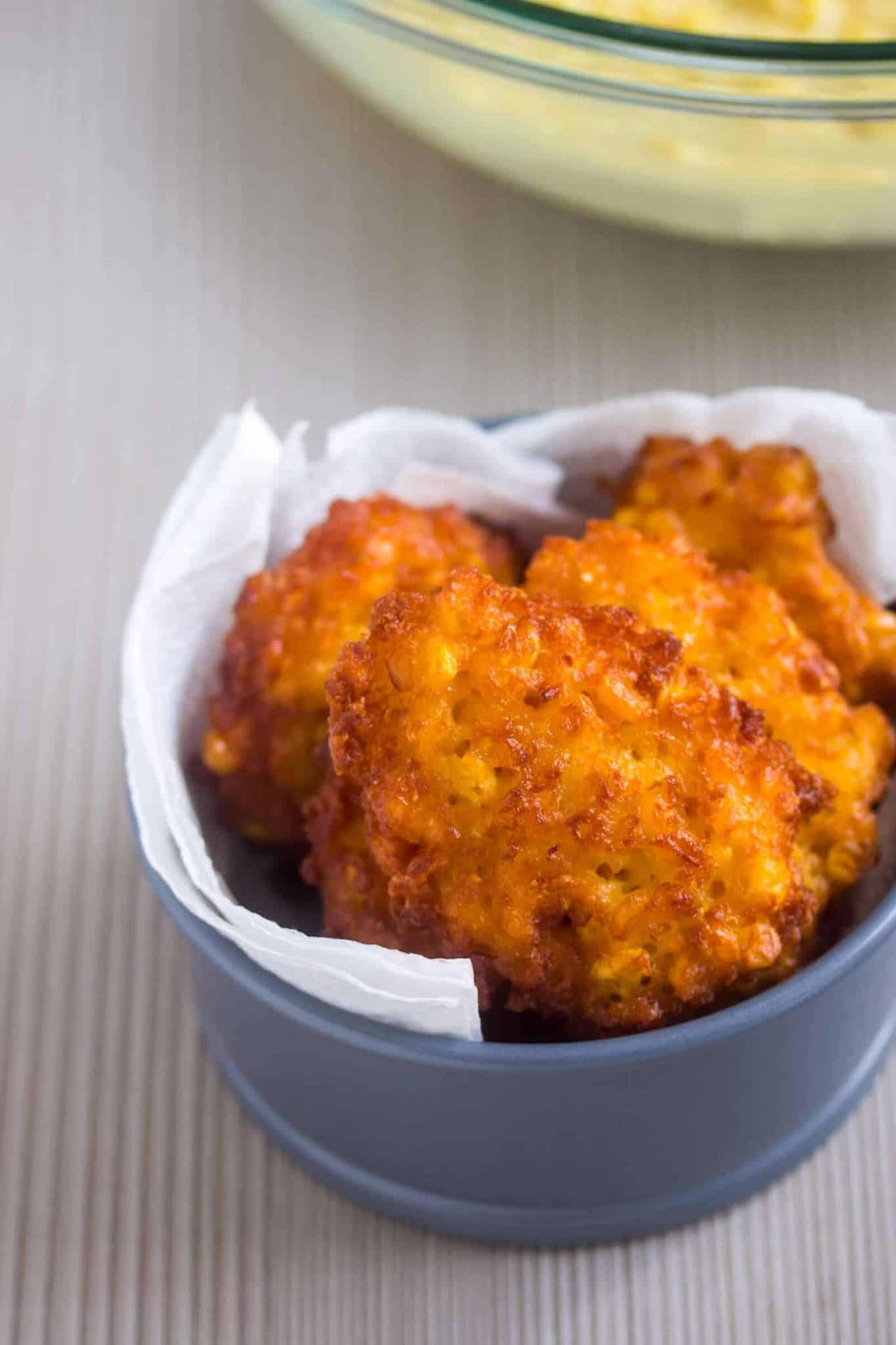 Sweet corn fritters on a paper towel tucked into a round container. 