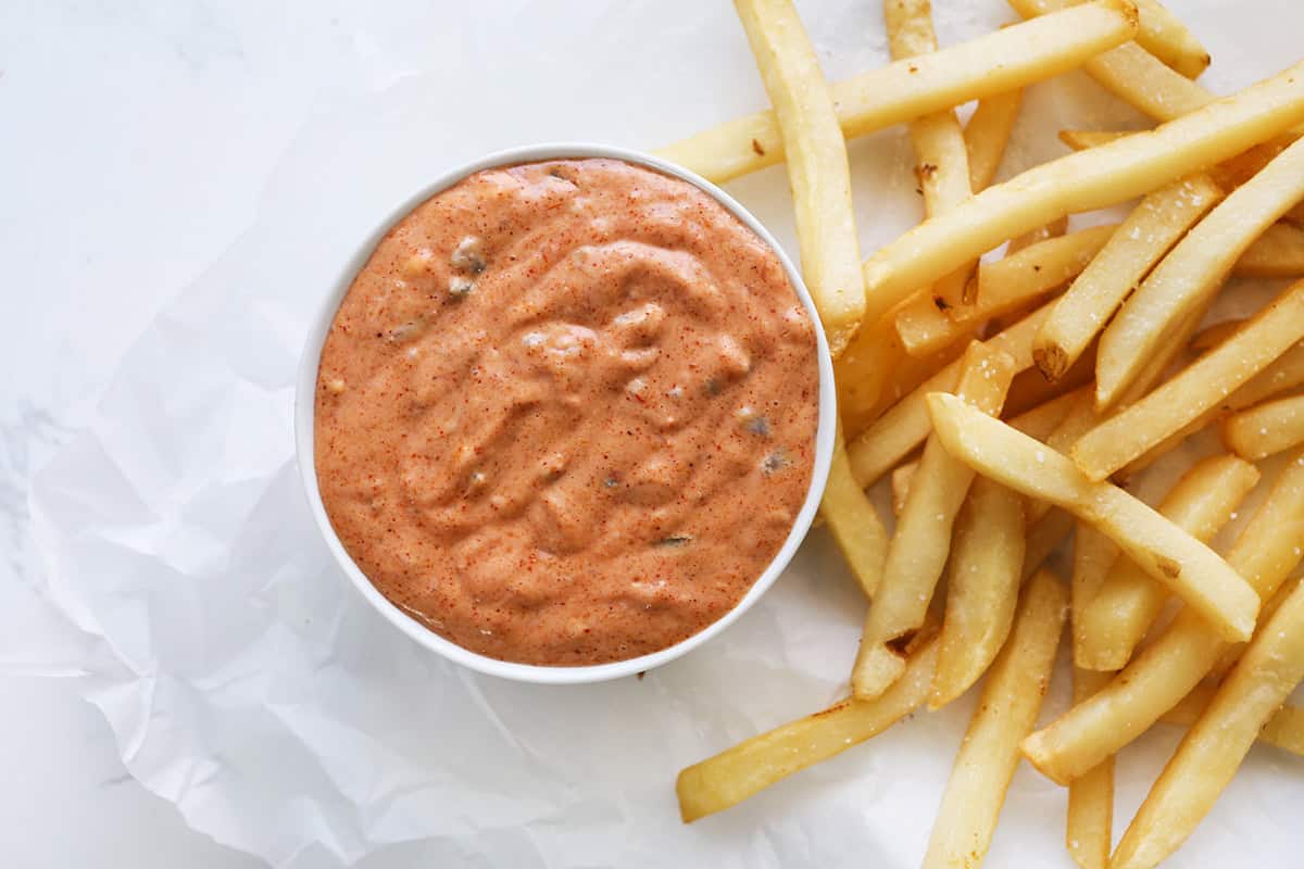 Top view of spicy sauce sitting next to a pile of fries.