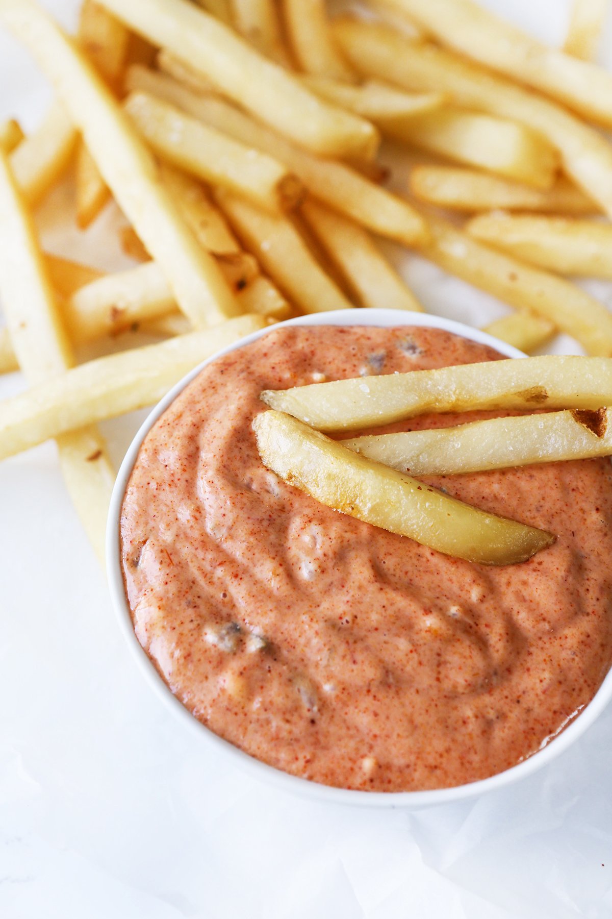 Bowl of crave sauce next to french fries.