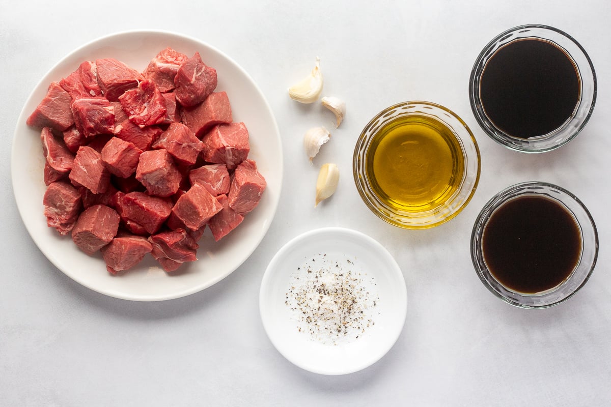 Cubed steak in a bowl surrounded by other ingredients to make steak bites.