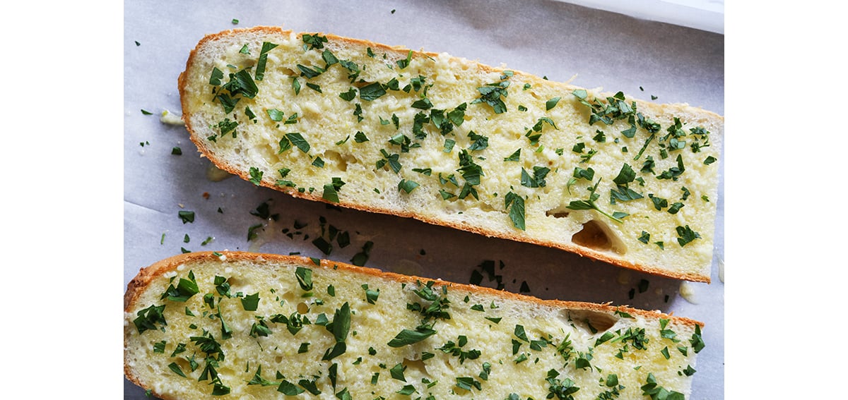 Herbed butter spread over cut sides of a loaf of French bread.